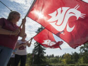 Jan Johnson, left and Joan Dengerink welcome students by waving crimson cougar flags on the first day of classes at Washington State University Vancouver on Monday. Johnson was the assistant to Hal Dengerink, founding chancellor. Joan Dengerink is his widow.