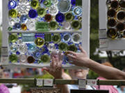 A &quot;window shopper&quot; feels one of Darla Lynn's recycled-glass creations Saturday at the Recycled Arts Festival at Esther Short Park.