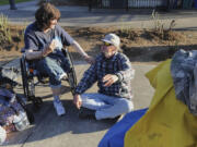 Kelli Jo Barclay, right, and Timothy Smith sit together before they head over for some soup handed out by Hot Soup Vancouver in the gazebo in Esther Short Park in Vancouver on Saturday.