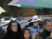 A Washington State Patrol trooper salutes in the rain as a procession of law enforcement vehicles pass by bearing the body of slain WSP trooper Tony Radulescu at the Mountain View Funeral Home on Feb. 24 in Lakewood, Wash. Radulescu was killed Thursday during a traffic stop in Gorst. A service for Radulescu begins at 1 p.m.