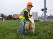 Benay Vincent collects litter found along Fourth Plain Road on Thursday in Vancouver.