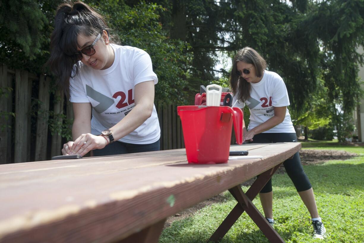 Volunteers Stefanny Caballero, left, and Sierra Smith paint a picnic table to spruce up the YWCA in Vancouver on Wednesday as part of the United Way's annual &quot;Day of Charitable Giving.&quot;