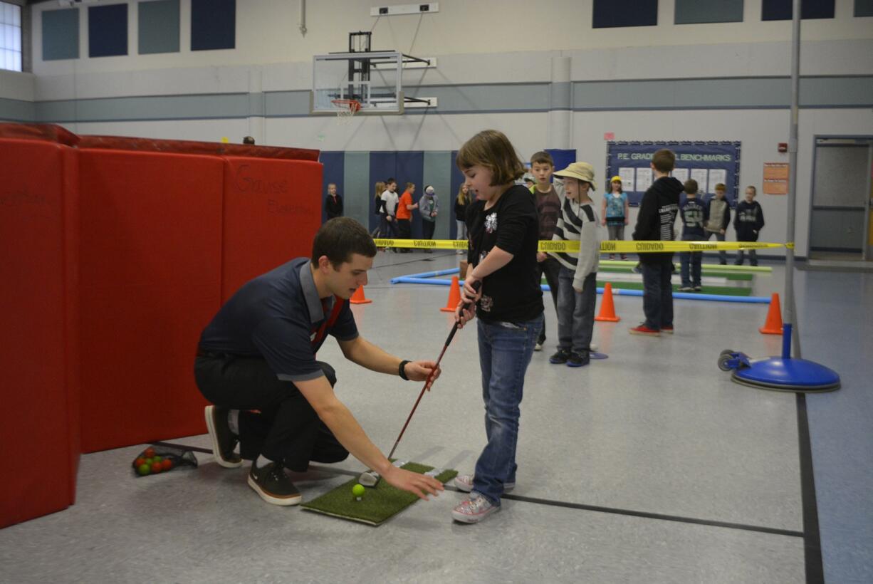 Washougal: Bryce Poulin of the Washington Youth Golf Academy at Camas Meadows shows Gause Elementary School student Jaedyn Gilson how to properly swing a golf club.