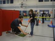 Washougal: Bryce Poulin of the Washington Youth Golf Academy at Camas Meadows shows Gause Elementary School student Jaedyn Gilson how to properly swing a golf club.