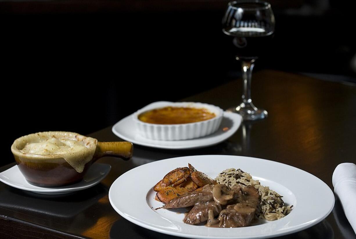 Pork Loin Roast With Carrots and Wild Rice, right, French Onion Soup, left, and Creme Brulee are featured dishes at Bones Steak and Chophouse in Battle Ground.