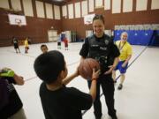 Photos by Steve Dipaola for the Columbian
Vancouver police Officer Julie Ballou accepts a basketball from a boy at Police Activities League of Vancouver summer camp at Orchards Elementary. Jenny Thompson, right, in yellow shirt, executive director of PAL, served as referee.