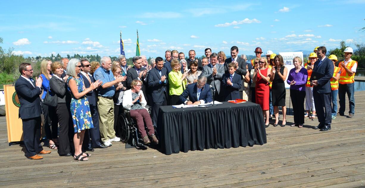 Office of the Governor
Sen. Don Benton, R-Vancouver, in blue shirt and khakis, applauds as Gov. Jay Inslee signs the transportation package into law last week. A few hours earlier, his office had announced he would attend the ceremony to voice his opposition to a &quot;raw deal for Clark County taxpayers and commuters.&quot;