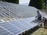 Bill Doile, left, and Will MacArthur install a solar panel for A