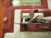 Trevor Wright, an inmate at the Clark County Jail, collects his commissary purchases through a small window of his jail pod.