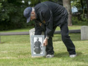 Military historian and volunteer Jack Buckmeir of Vancouver places a photograph of Moses Williams at his grave in the Vancouver Barracks Post Cemetery on Thursday, in honor of Memorial Day.