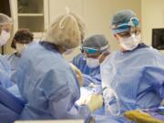 Dr. Allen Gabriel, second from right, injects Botox into the pectoral muscle of a patient during breast reconstruction surgery Sept. 2 at PeaceHealth Southwest Medical Center.