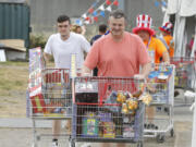 Eddie McGrath, from left, his father, Ed McGrath, and TNT Fireworks Warehouse's general manager, Beau Leach, push the McGraths' fireworks haul to their vehicle Sunday.