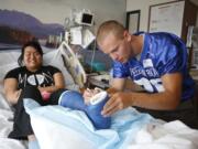 Freedom Bowl Classic football players visiting children in the hospital. Tucker Anderson of Hockinson signs cast for patient Chloe Ouchida, of Portland, age 16.