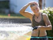 JR Ralston rubs water on her head as she waters her garden at her Felida home on Monday August 11, 2014.