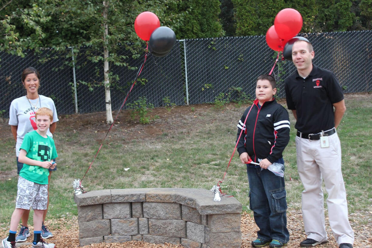 Image: Endeavour Elementary School fifth-graders Kyle Wilke, left, and Junior Martinez stand with Principal Lauren Hopson and Associate Principal Stuart Anderson next to the school's new &quot;Grizzly Bench,&quot; which is meant to be a safe place for students to sit during recess when they are in need of a friend to play with.