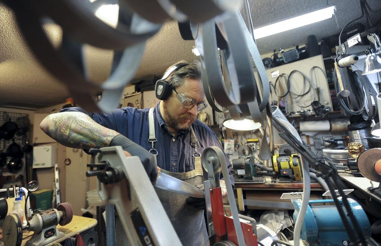 Eliot Smith sharpens a knife Tuesday in his shop at his home in Vancouver.