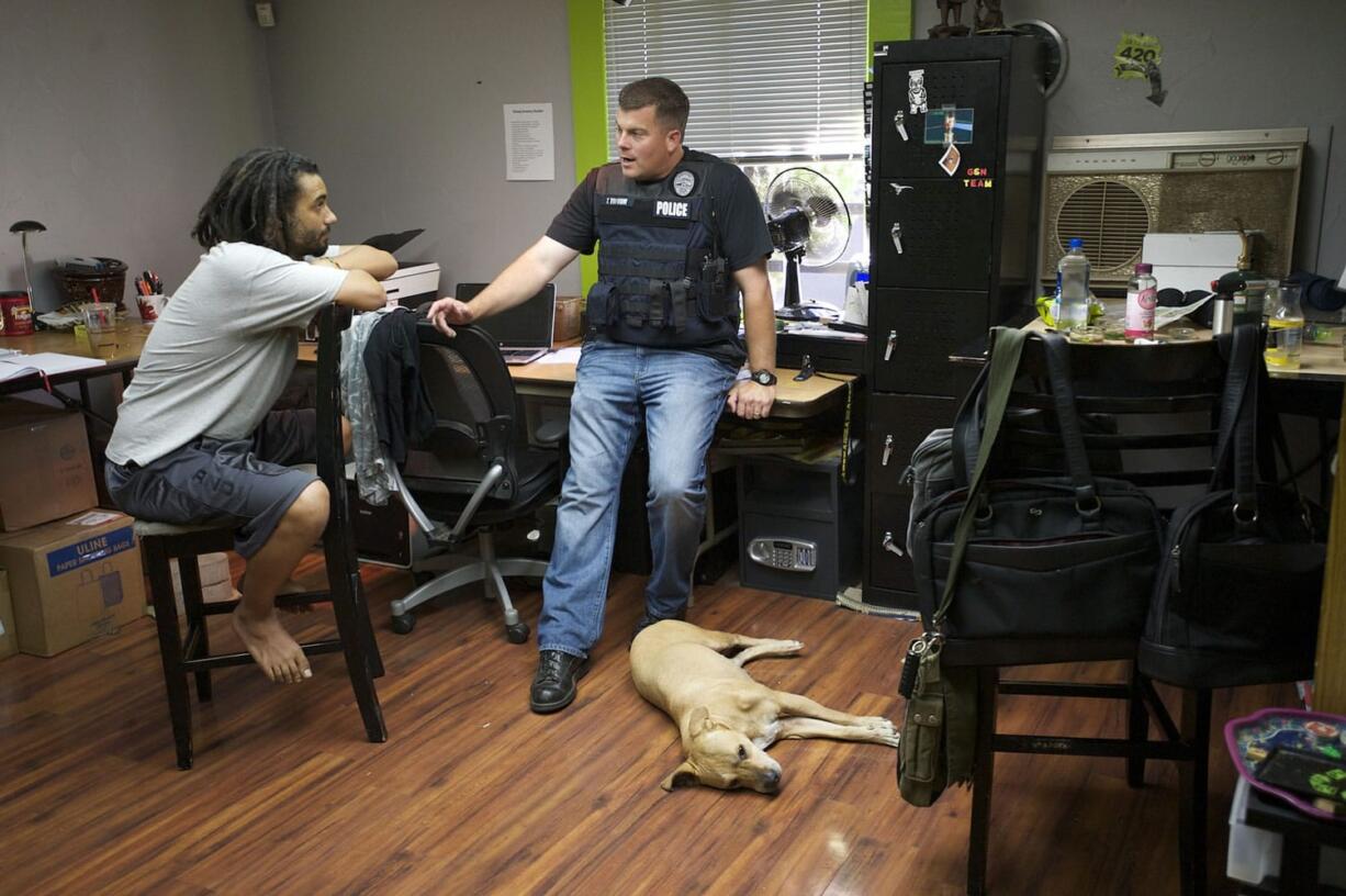 Adam Alexander, the owner of Grow Systems Northwest, is interviewed by Vancouver police officer Tom Topaum after a search warrant was executed at the business Thursday.