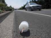 A motorist traveling on Northeast Ward Road passes discarded trash in the bike lane Wednesday afternoon, August 26, 2015.