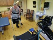 Physical therapist assistant Kathy Wiederman helps Kathy Hammersley walk using a walker at the Cascade Park Care Center.