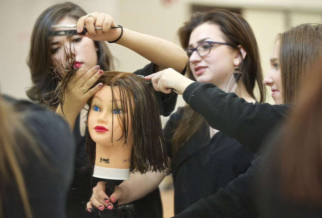 Photos by Zachary Kaufman/The Columbian
Cosmetology students, from left, Cristal Solorio, 19, Maddie Ponder, 17, and Jordan Harp, 17, repair a mannequin's chemically damaged hair Wednesday at the Clark County Skills Center. Harp got distracted and accidentally left bleach on the mannequin's head for two days.