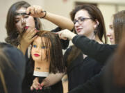 Photos by Zachary Kaufman/The Columbian
Cosmetology students, from left, Cristal Solorio, 19, Maddie Ponder, 17, and Jordan Harp, 17, repair a mannequin's chemically damaged hair Wednesday at the Clark County Skills Center. Harp got distracted and accidentally left bleach on the mannequin's head for two days.