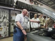 Clark College instructor Bruce Music, left, teaches offenders about changing belts in an automotive repair class at Larch Corrections Center.