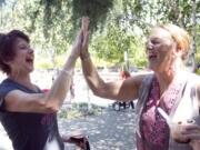 Susan Pagel of Battle Ground, left, high-fives fellow breast cancer survivor Becky Ewer at a social event sponsored by the nonprofit Pink Lemonade Project this summer in Jamison Square in Portland.