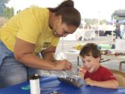 Volunteer Jessica Clay helps Patrick Gallegos, 6, of Vancouver plant sunflower seeds in a plastic-bottle planter at the Evergreen Habitat for Humanity first Remaker's Fair to benefit the Women Build program.