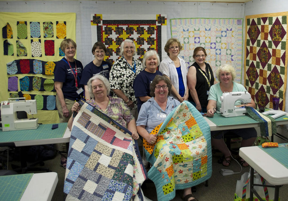 Northeast Hazel Dell: Project Linus members pose with quilts they made for children in need during a recent gathering at A Quilt Forever. Back row, from left: Lys Leitner, Lori Tate, Brenda Mitchell, Sandy Hubbard, Lynda Van de Grift, Nancy Foley-Hibberd, Cindy Strom.