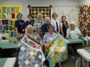 Northeast Hazel Dell: Project Linus members pose with quilts they made for children in need during a recent gathering at A Quilt Forever. Back row, from left: Lys Leitner, Lori Tate, Brenda Mitchell, Sandy Hubbard, Lynda Van de Grift, Nancy Foley-Hibberd, Cindy Strom.