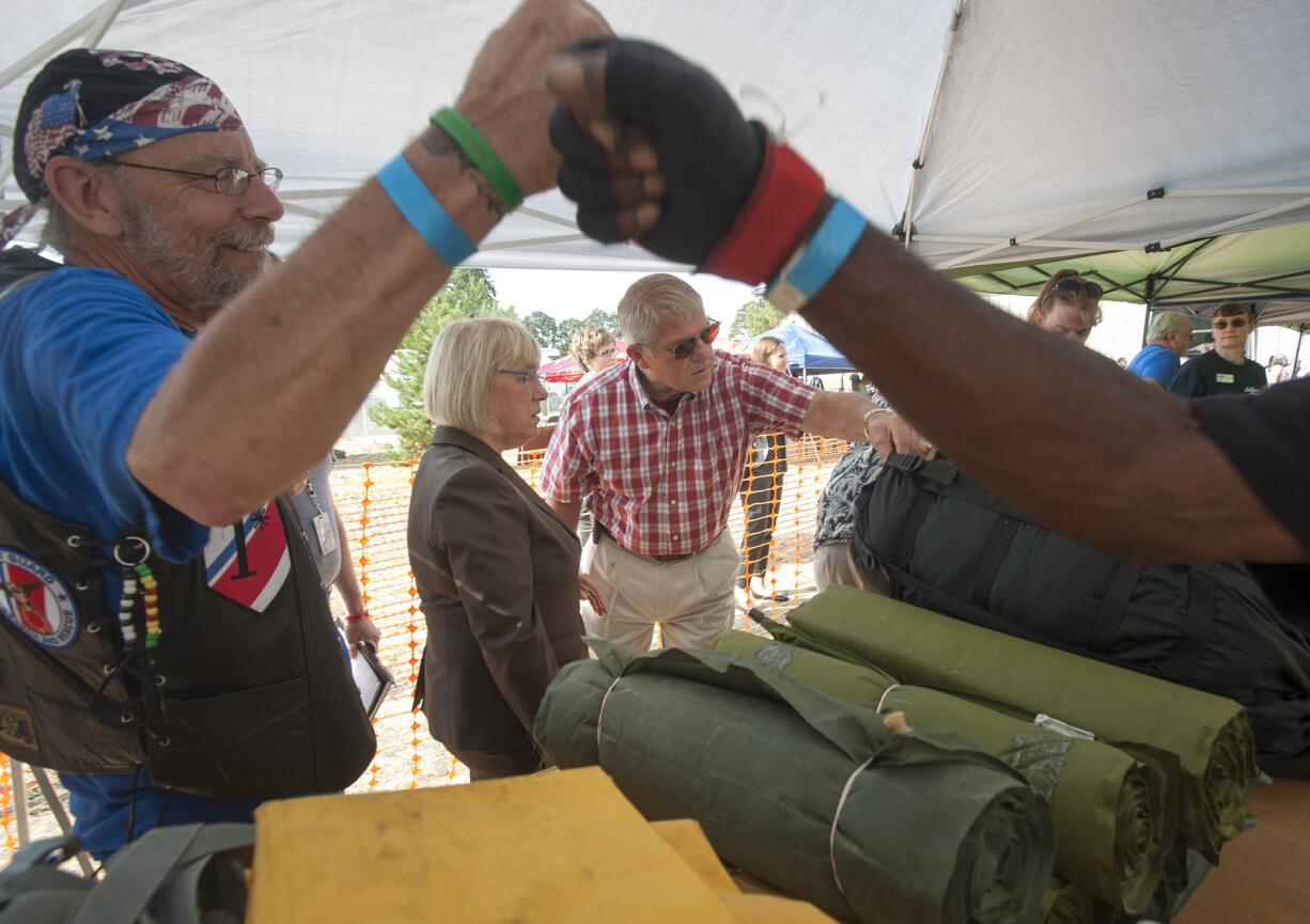 As stand-down director Nick Herber, left,  greets a volunteer, Vancouver City Councilor Larry Smith shows U.S. Sen. Patty Murray, center, the military surplus supplies available to veterans at Wednesday's event.