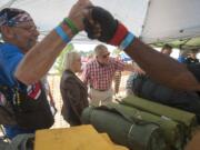 As stand-down director Nick Herber, left,  greets a volunteer, Vancouver City Councilor Larry Smith shows U.S. Sen. Patty Murray, center, the military surplus supplies available to veterans at Wednesday's event.