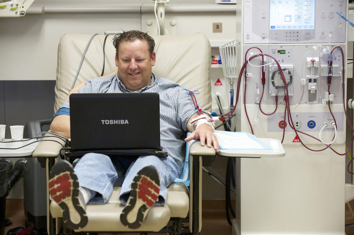 Photos by Steven Lane/The Columbian
Scott Warren passes the time on his computer during a recent four-hour dialysis session at DaVita Vancouver Dialysis Center. Warren's kidneys failed three years ago. Since then, he's been on a mission to find a living kidney donor.