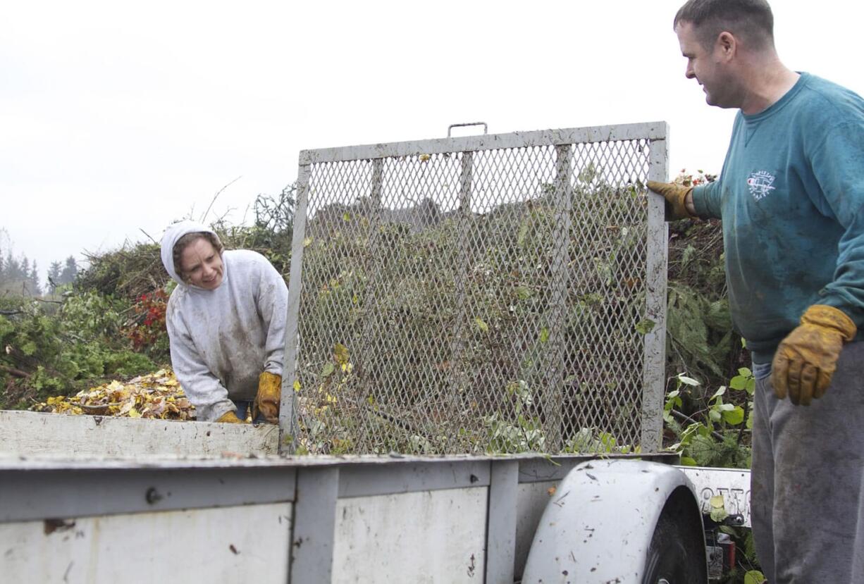 Kandi White of Hockinson and her husband, Travis, finish unloading yard debris Sunday at H &amp; H Wood Recyclers in the Orchards area.