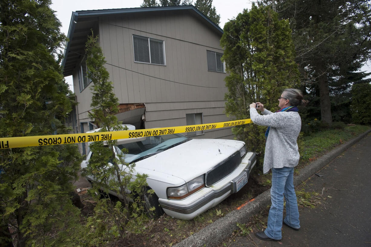 Patti Brockman takes photos for insurance purposes of a car that struck and got stuck in the house she looks after.