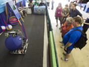 Visitors stop to watch a demonstration of a robot throwing a ball at the Clark County Fair. The 4-H high school robotics team made the robot for the annual robotics competition.