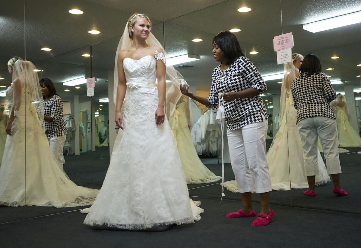 Bridal consultant Crystal Payne helps bride-to-be Cheney Ryder, 23, of Ridgefield try on wedding dresses July 23 at The Hostess House.