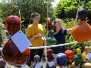 Mona Fuerstenau, right, and Ben Fisher make a selection from Dick Mills' gourd birdhouses at Art in the Garden in Brush Prairie on Sunday.