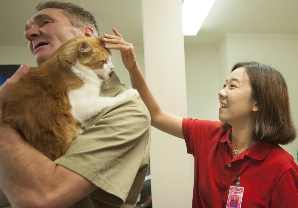 South Korean university student Woo Jeong Kim strokes inmate Harold Bain's cat, Mikey, Thursday at Larch Corrections Center.