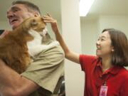 South Korean university student Woo Jeong Kim strokes inmate Harold Bain's cat, Mikey, Thursday at Larch Corrections Center.