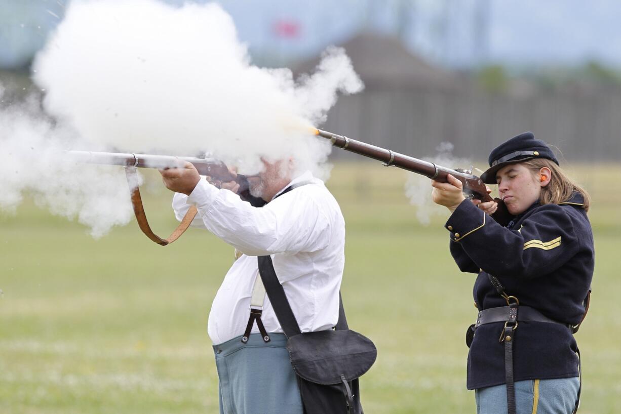 Flame flares from the  barrels of volunteers John Miller, left, and Emily Wattez as they fire their muskets during Fort Vancouveru2019s annual black-powder training.