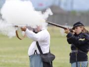 Flame flares from the  barrels of volunteers John Miller, left, and Emily Wattez as they fire their muskets during Fort Vancouveru2019s annual black-powder training.