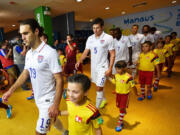 Mallory Stonier, 9, walks onto the field at the World Cup in Manaus, Brazil, with Team USA player Graham Zusi.