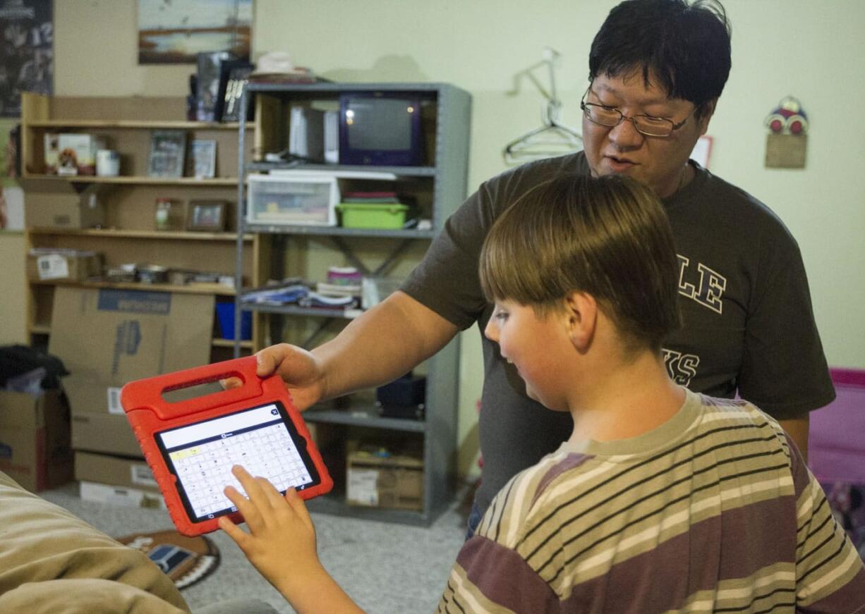 Bryce Smith holds an iPad while his son Dylan Smith, 10, tells him what activity he wants to do after dinner. Dylan is a nonverbal child on the autism spectrum.