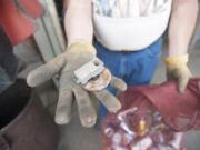 Air Water Earth Recycling owner Paul Hardman shows bits of tin removed by a magnet as he sorts through aluminum cans this week.