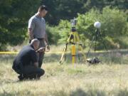 Detectives Joe Swenson, left, and Scott Gilberti search a field in Ridgefield as part of a homicide investigation. The body of a man was apparently dumped in a field just south of 179st Street near 15th Avenue in summer of 2015.