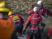 Firefighters from the regional technical rescue team recover a body in the Little Washougal River on Monday.