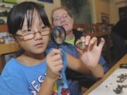 Patricia Colburn, left, and her mother, Denise Colburn, examine a small animal skull that Patricia found during her owl pellet dissection at the Fall Family Field Trip Day at the Columbia Springs environmental education center on Saturday.