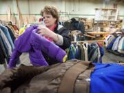 Robin Anderson, from the Rotary Club of Greater Clark County, selects children's coats Friday at the Friends of the Carpenter center.