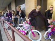 Jennifer Brinkman, center, helps wheel brand-new bicycles and helmets into the Department of Social and Health Services building in West Vancouver on Wednesday morning. The bikes were donated by Wal Mart and assembled and delivered by Waste Connections employees and others.